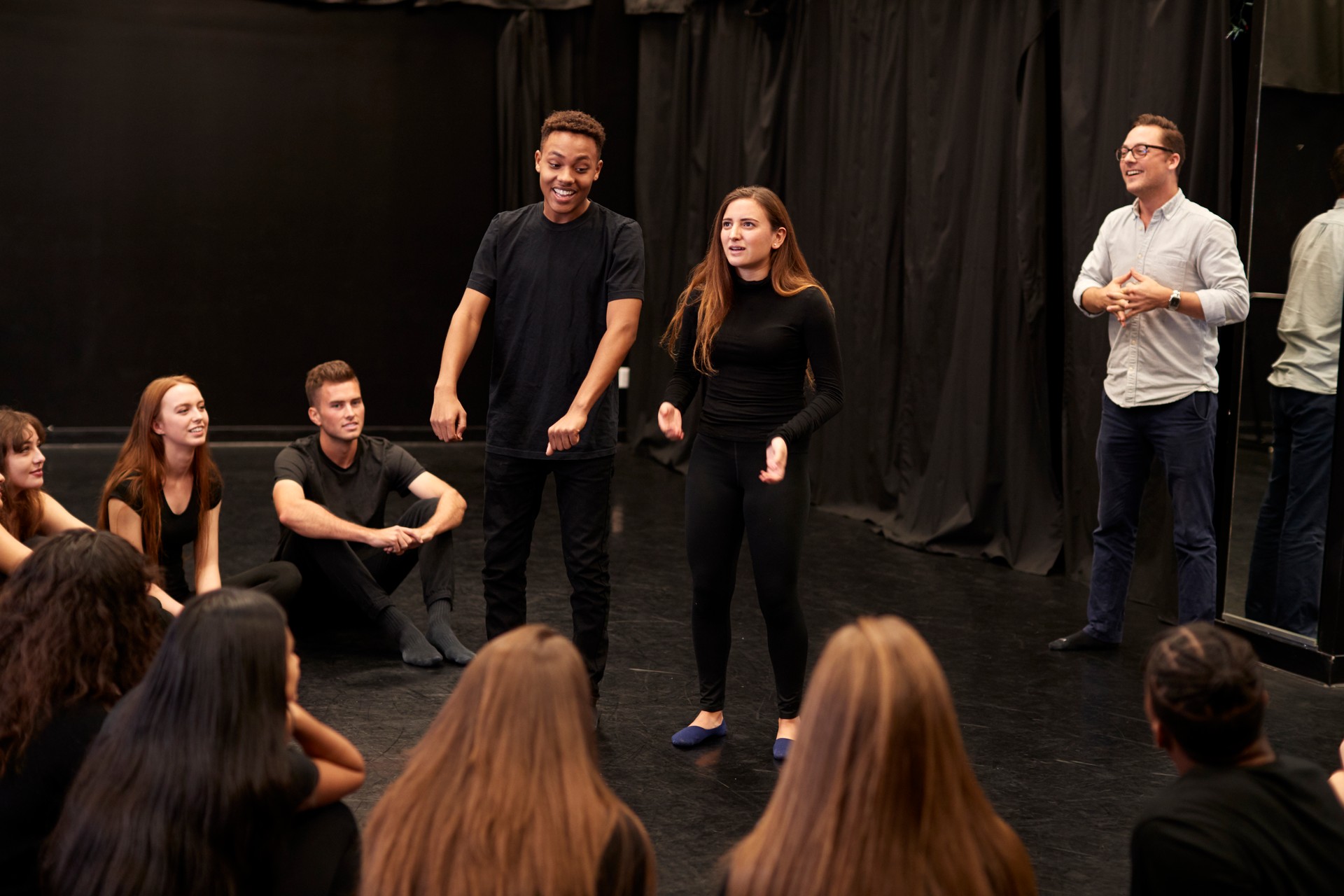 Teacher With Male And Female Drama Students At Performing Arts School In Studio Improvisation Class